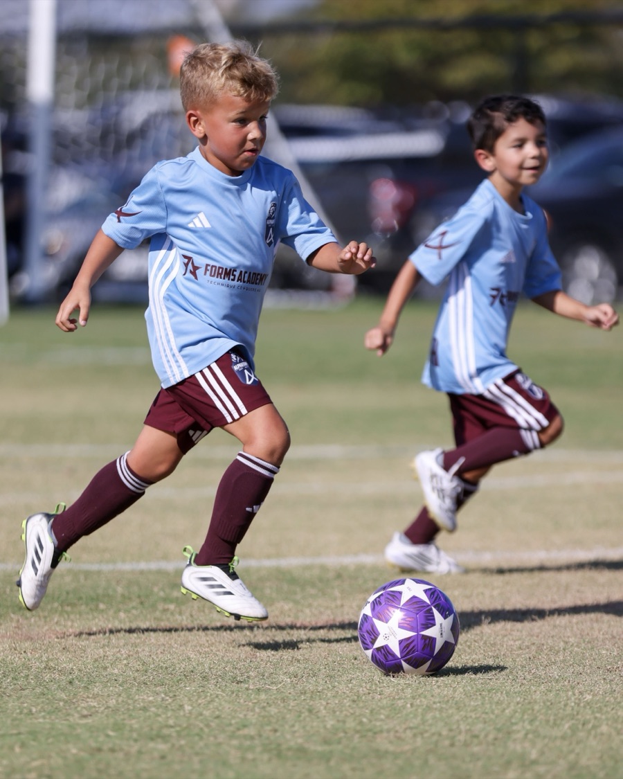 A Forms Academy player driving at a defender with the ball
