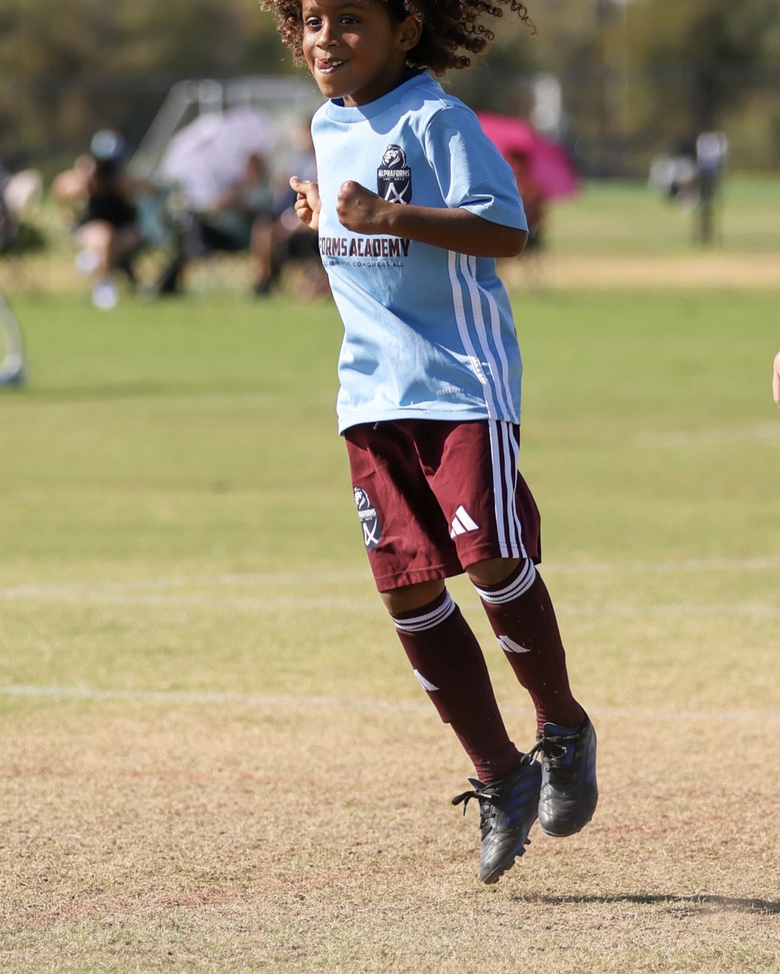 A Forms Academy player smiling as he runs during a match